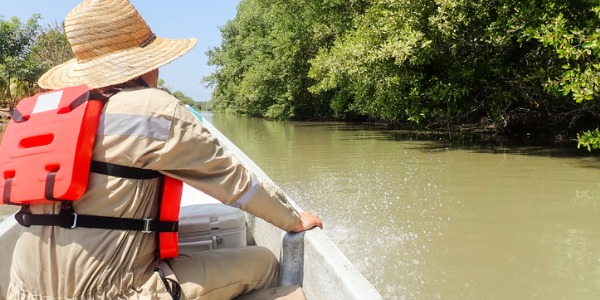 A wildlife biologist traveling on a boat on the river.