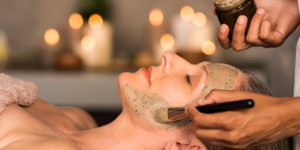 An esthetician applying a mask treatment on one of their clients.