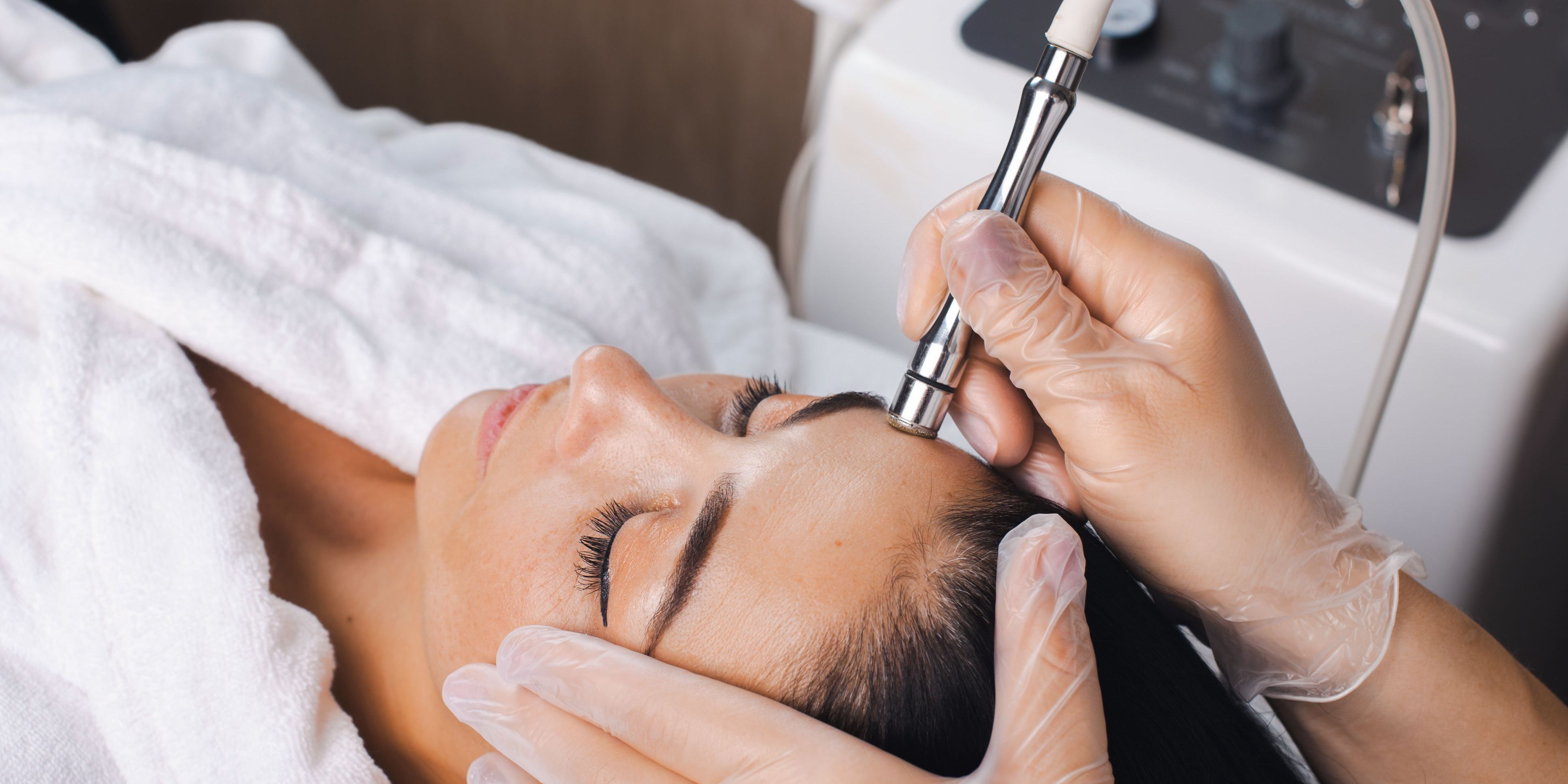 A medical esthetician using microdermabrasion to improve a client's skin.
