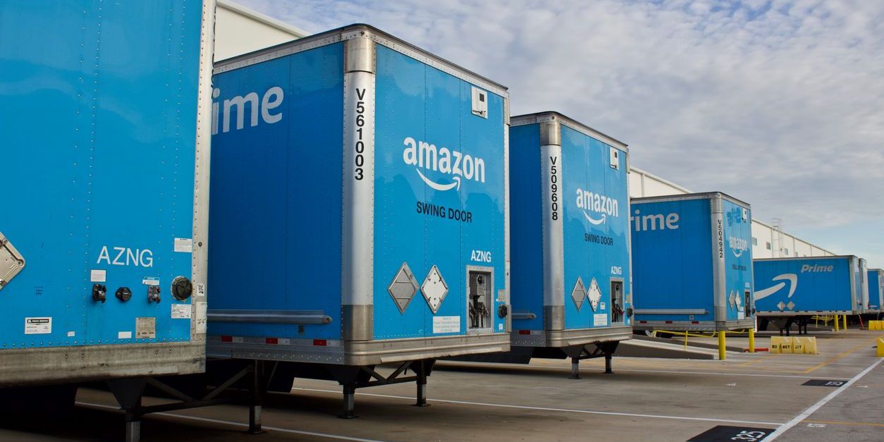 Multiple Amazon trailers backed into bays at a distribution center.