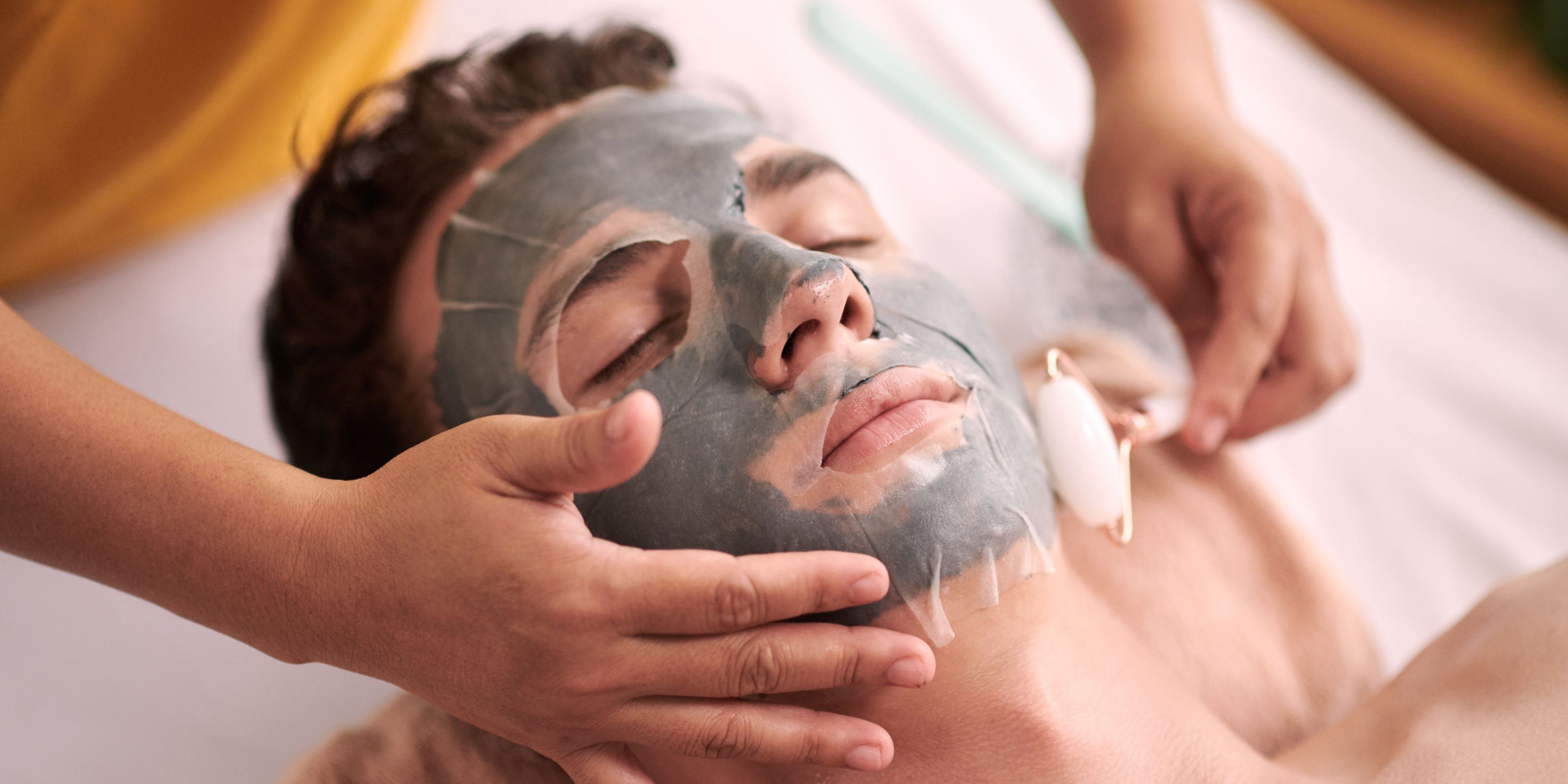 A men's skincare specialist applying a facial treatment to a male client.