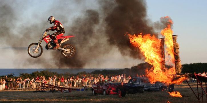 A stuntman jumping through a ring of fire on a motorcycle.