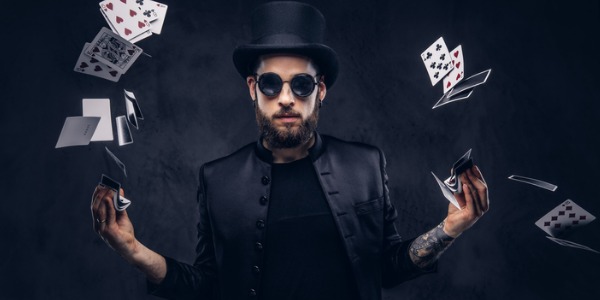 A magician facing the camera with floating cards coming from both hands.