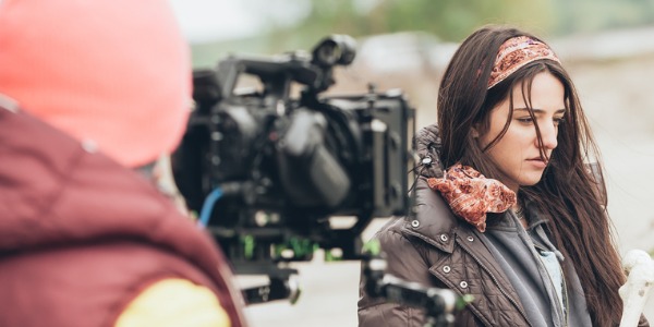 An actress working outside, playing a character in a film.